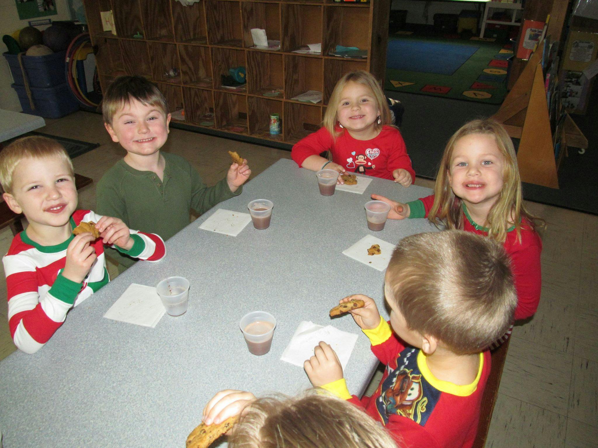 Children sitting at a table with cookies and drinks