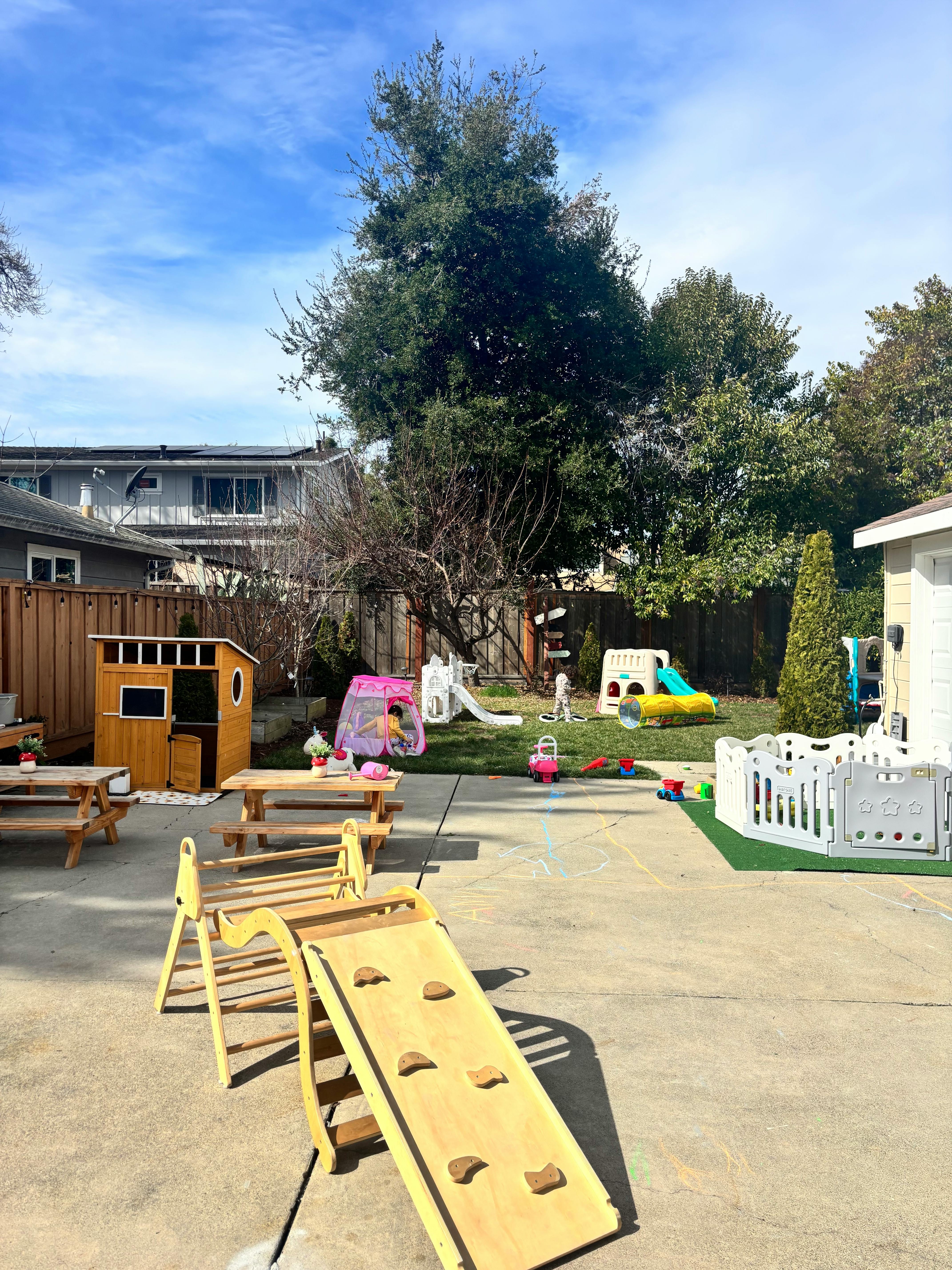 Outdoor play area with various play structures, including a slide and climbing ramp