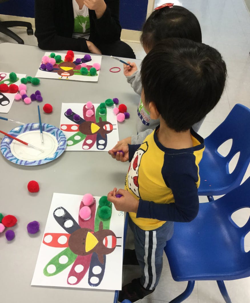 Child making a turkey craft with pom-poms