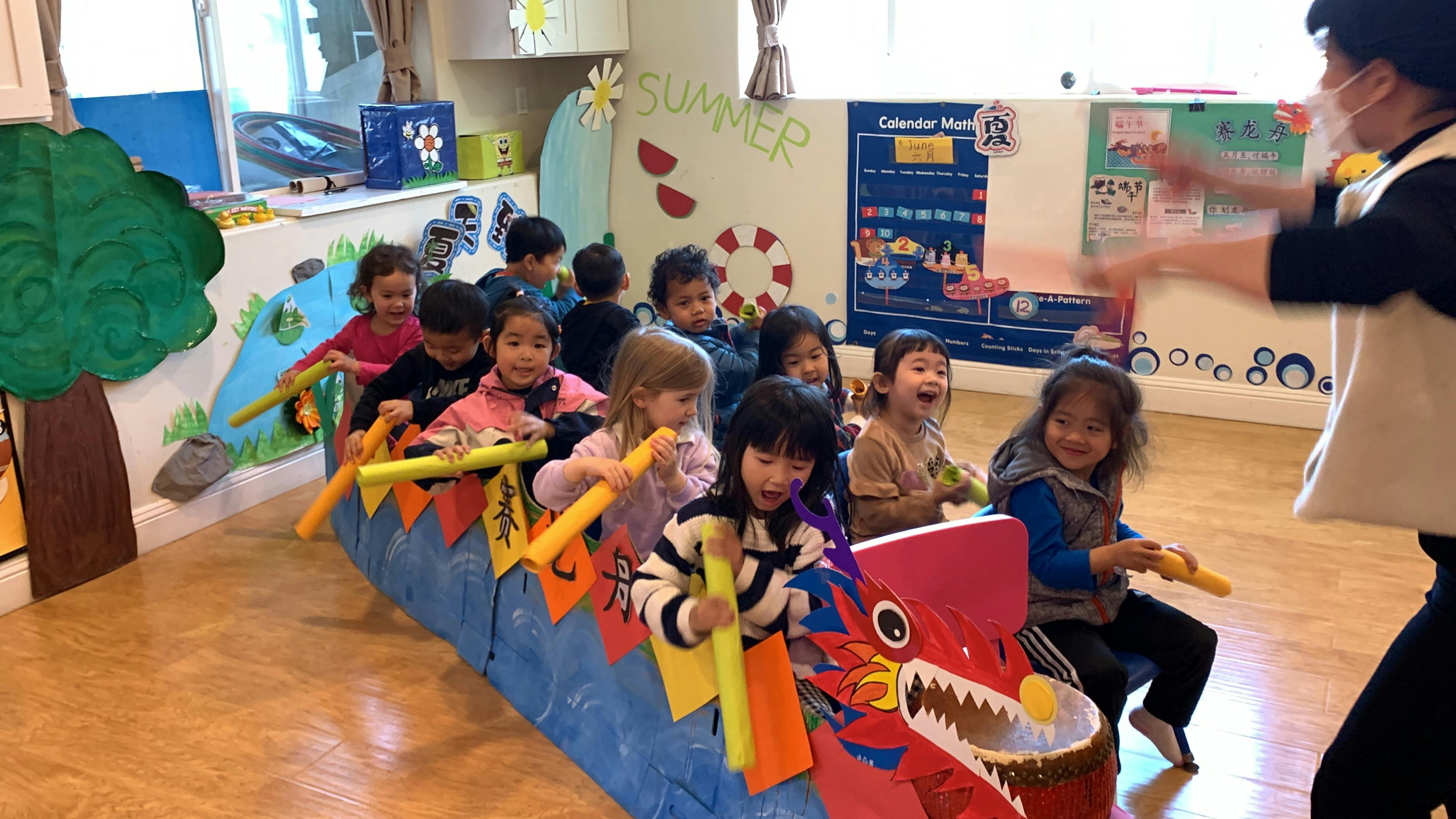 Children in a classroom playing with a dragon boat prop