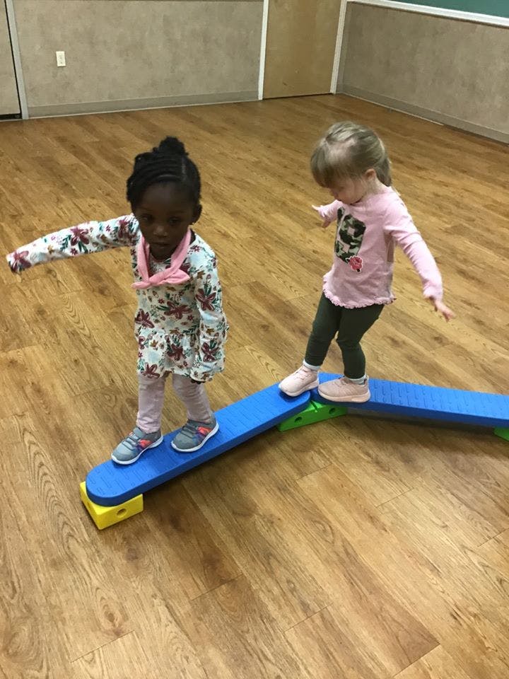 Two children balancing on a blue beam