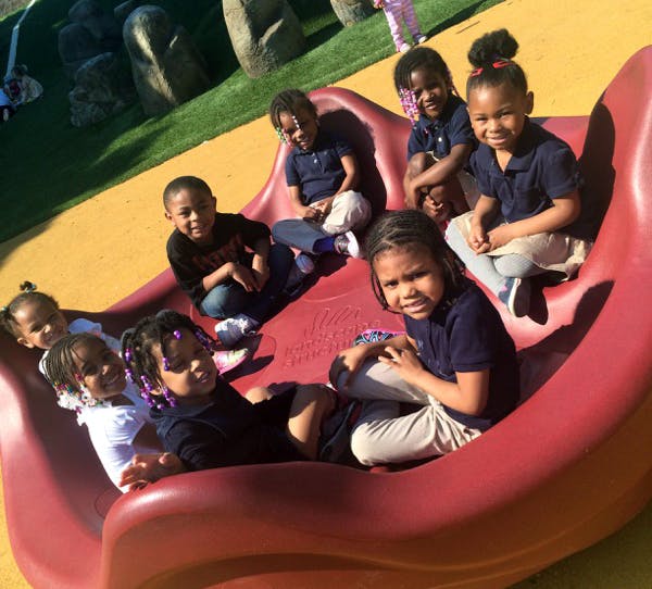 Group of children sitting on a red playground slide