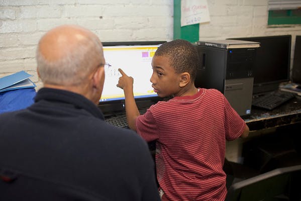 Adult and child looking at a computer screen, child pointing at screen