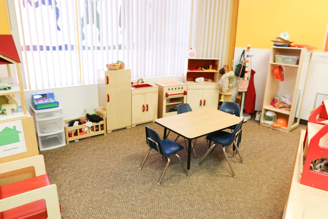 Playroom with small table and chairs, toy kitchen, and shelves