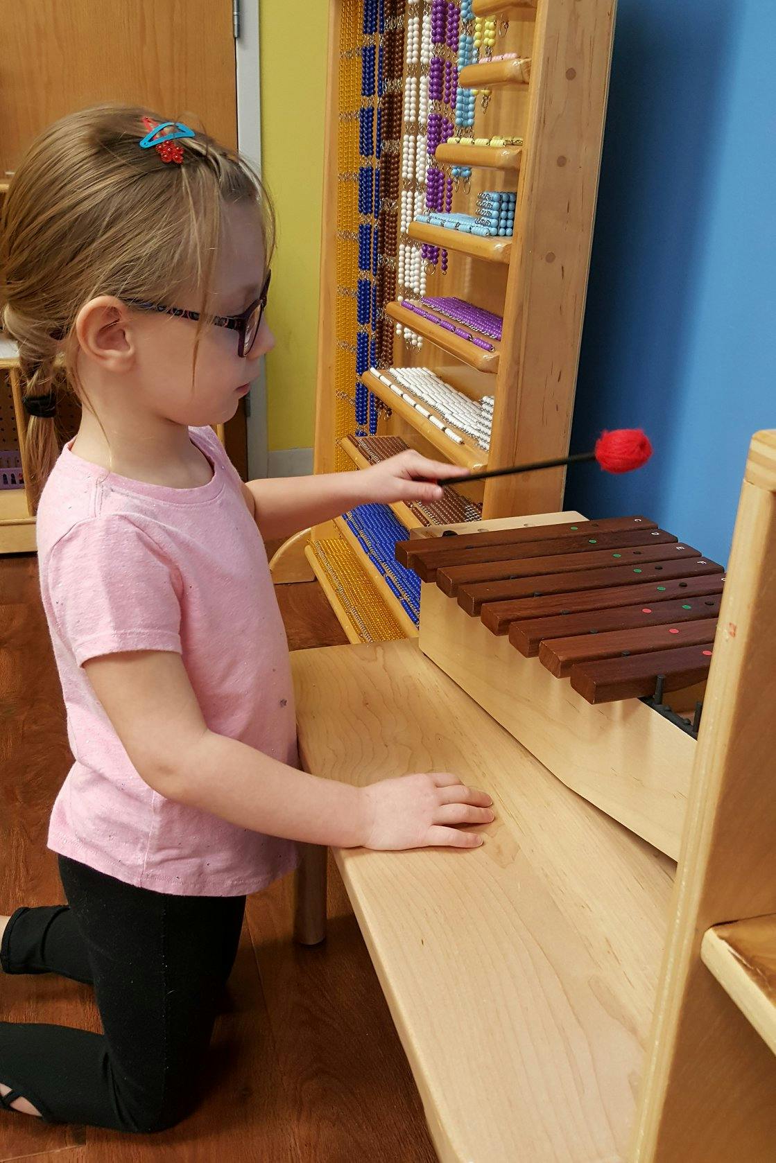Child playing a xylophone with a mallet