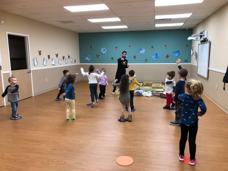 Adult leading a group of children in an activity in a classroom