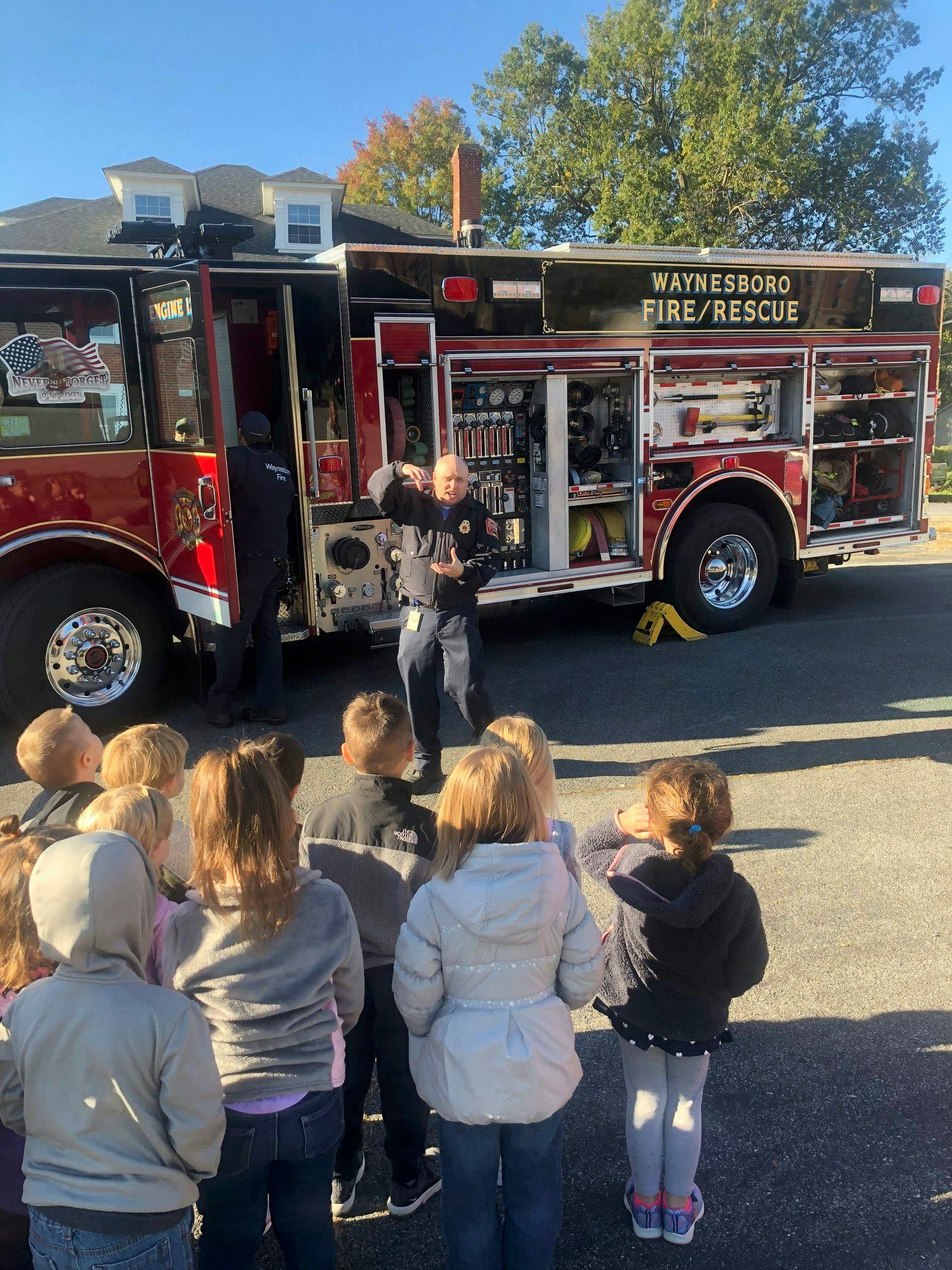 Firefighter speaking to a group of children in front of a fire truck