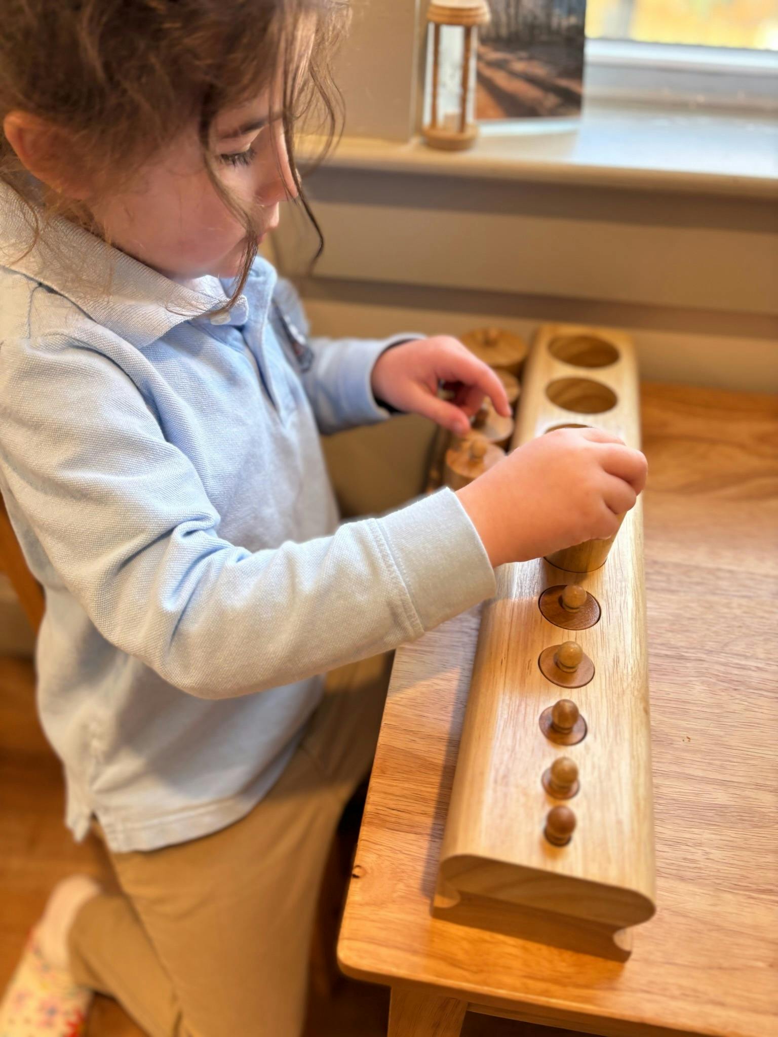 Child playing with a wooden cylinder block Montessori toy