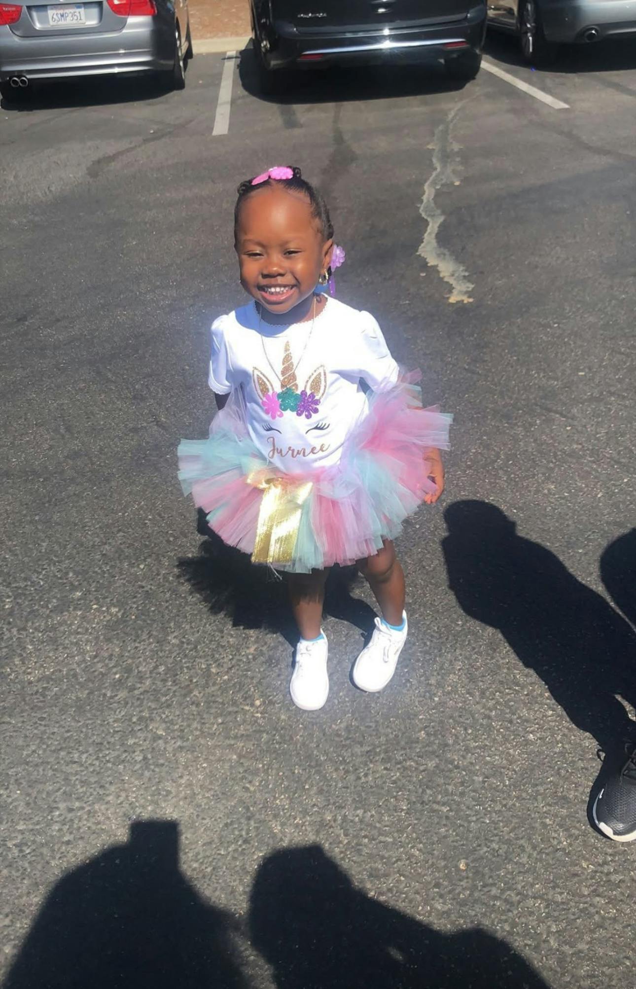 Child wearing a unicorn t-shirt and tulle skirt standing in a parking lot