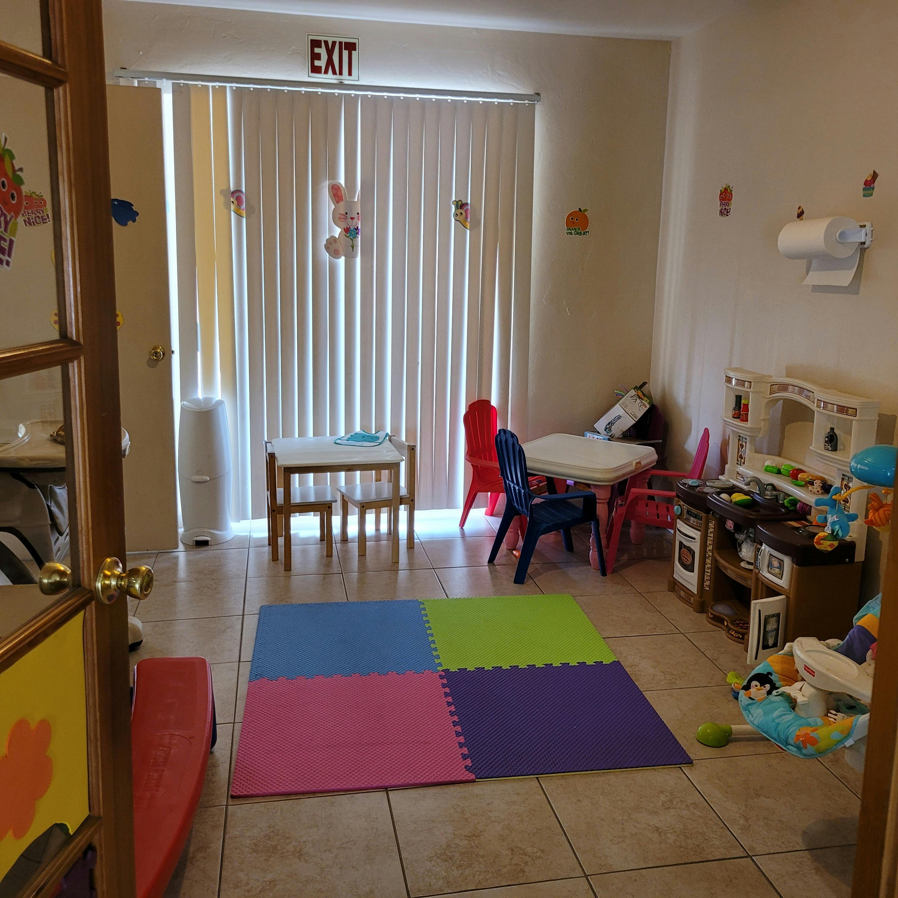 Playroom with colorful floor mats, small tables and chairs, and toys