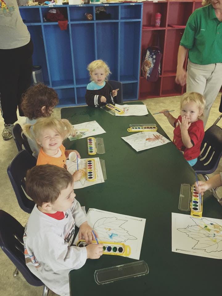 Children painting at a table in a classroom
