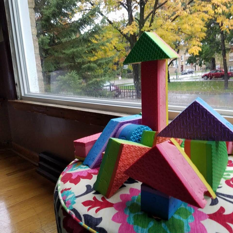 Colorful foam blocks arranged on a patterned cushion by a window