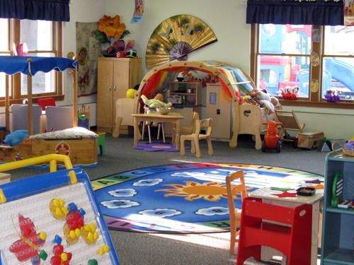 Playroom with a blue rug, play kitchen, and various toys