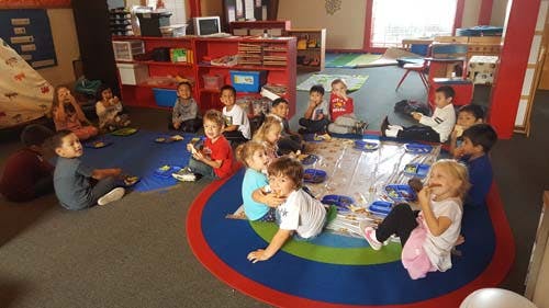 Children sitting on a rug in a classroom