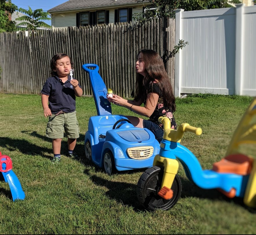 Person and child blowing bubbles in a yard