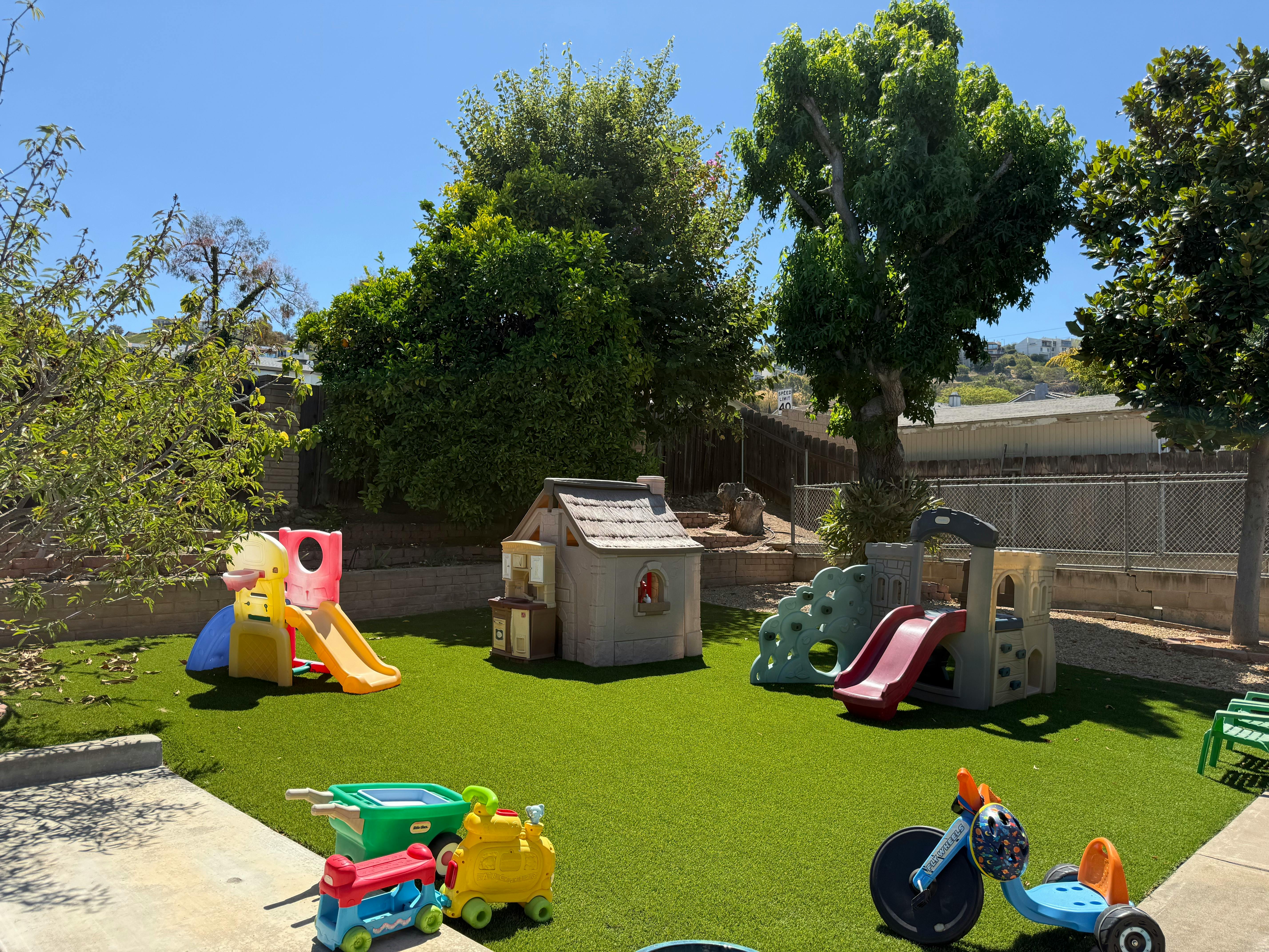 Plastic playhouse and playground equipment on an artificial grass backyard