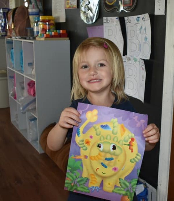 Child holding up a colorful paper craft of an animal