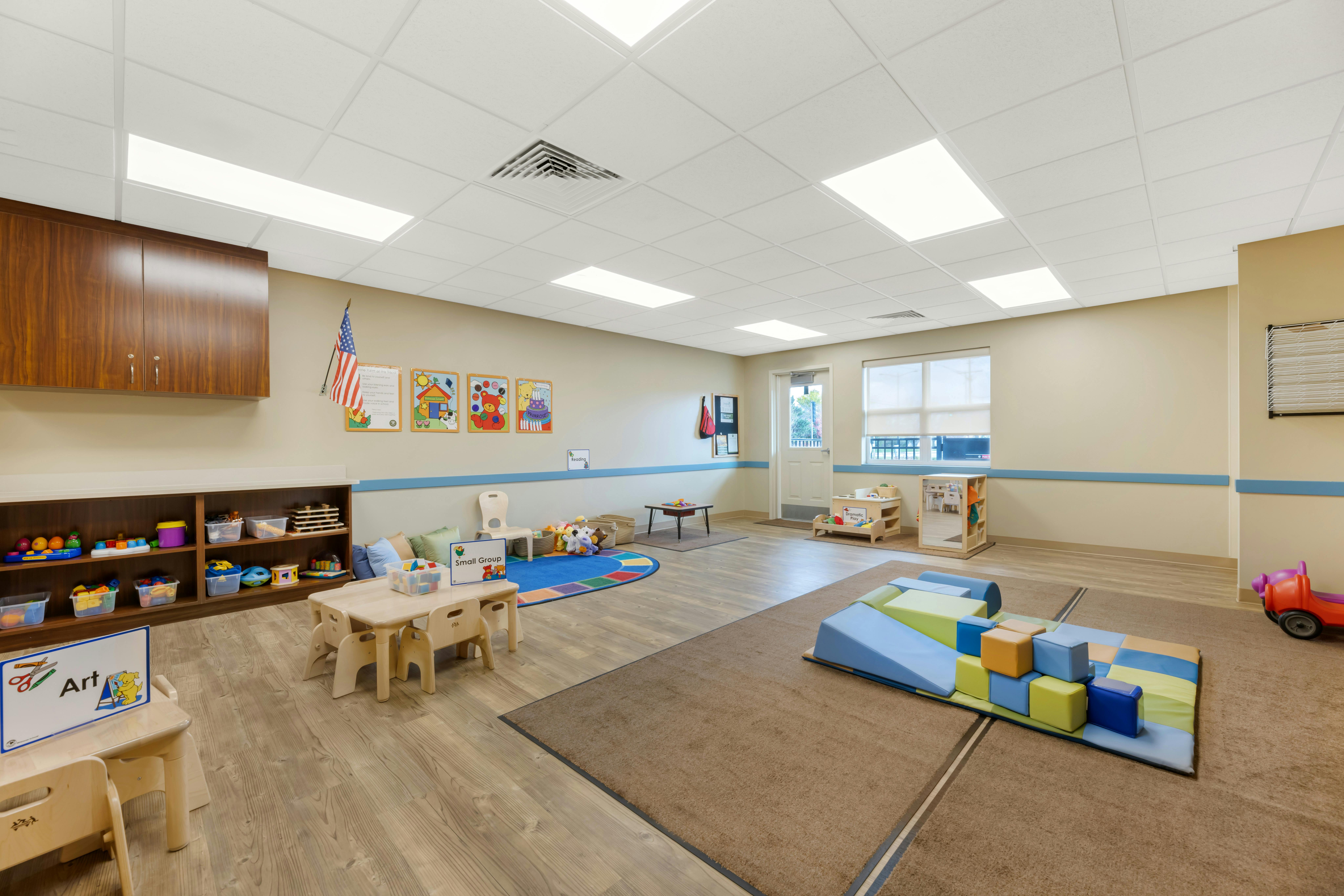 Empty colorful children's classroom with small tables, chairs, and play mats