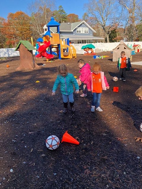 Children playing with a soccer ball and cones on a playground