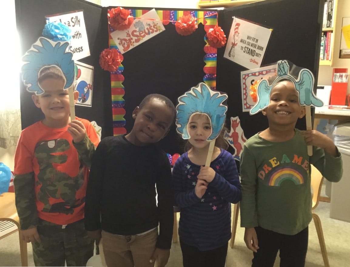 Four children holding up blue paper cutouts on sticks