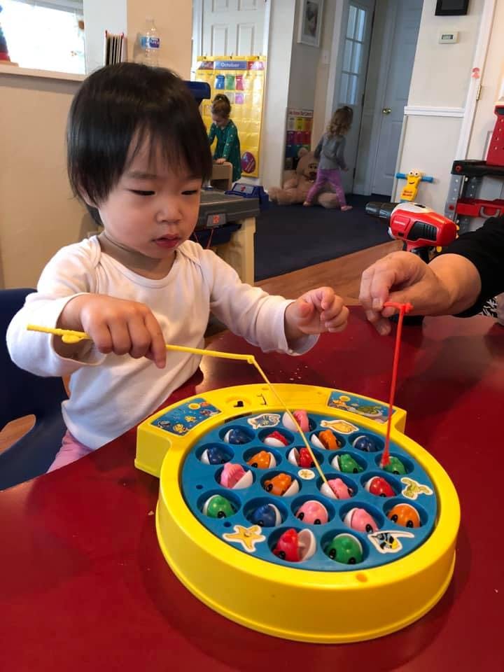 Child playing a fishing game with an adult