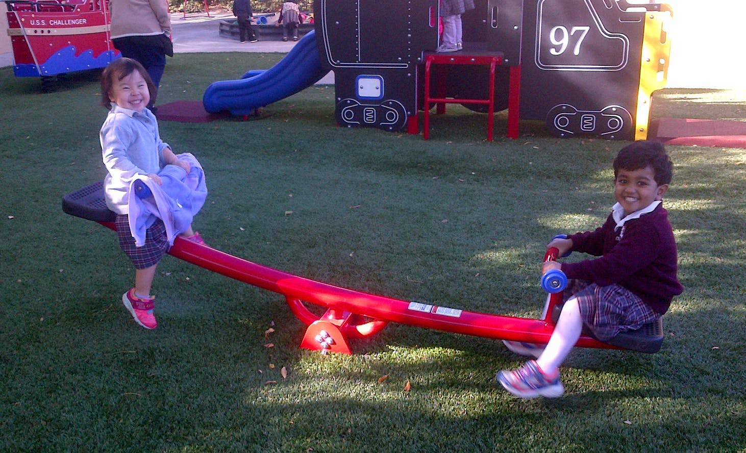 Two children on a seesaw in a playground