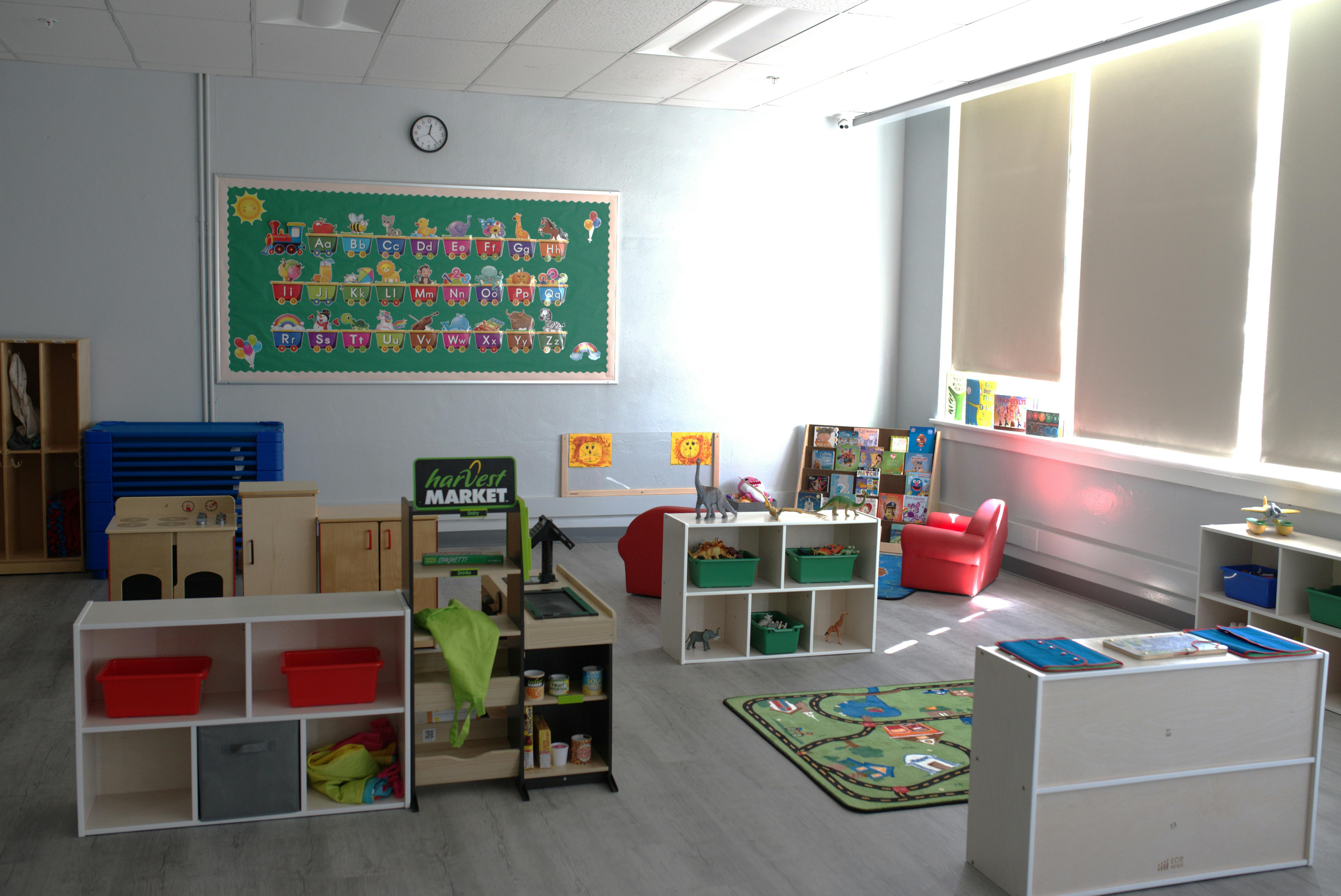 Empty classroom with shelves, toys, and a green bulletin board