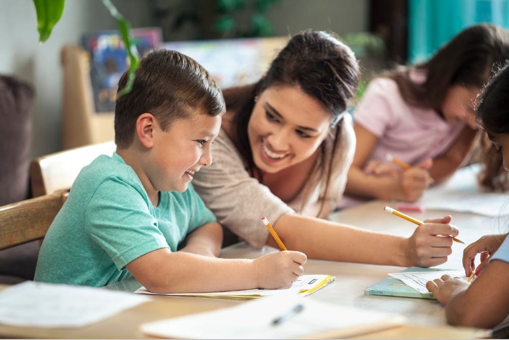 Adult and children writing at a table