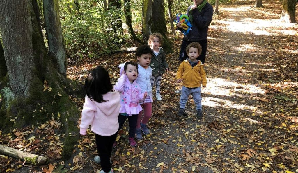 Children and an adult on a path in a wooded area