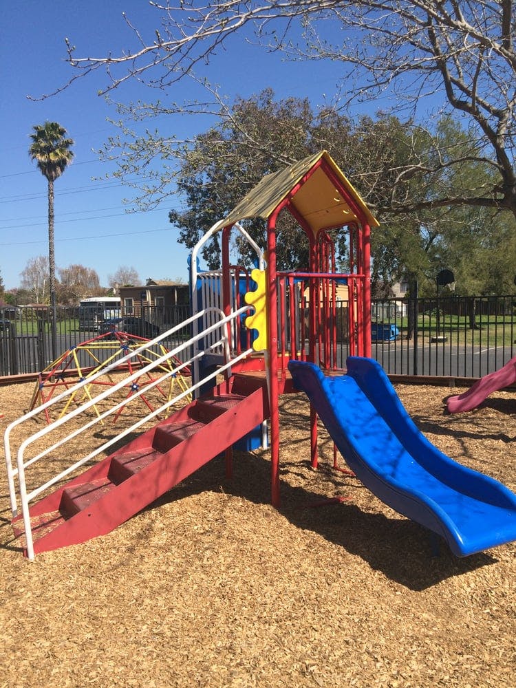 Playground structure with red stairs, blue slide, and climbing dome