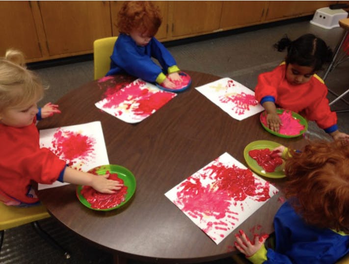 Children doing handprint painting at a table