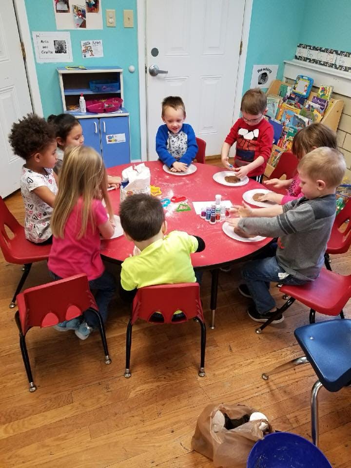 Children sitting around a red table with plates and plates