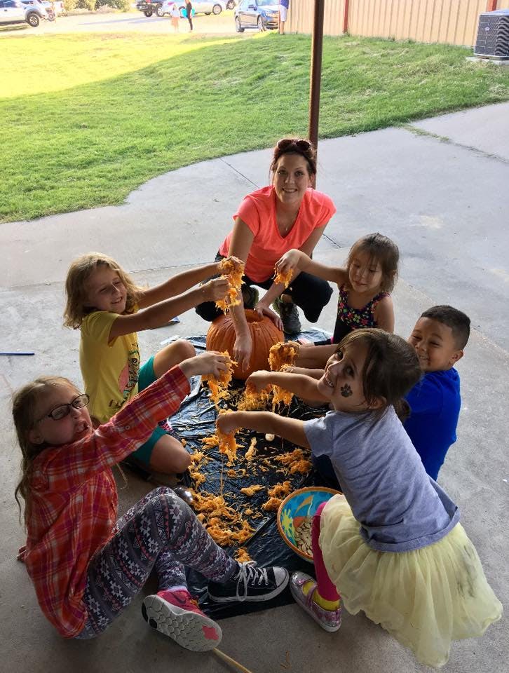 Adult and children carving pumpkins outdoors