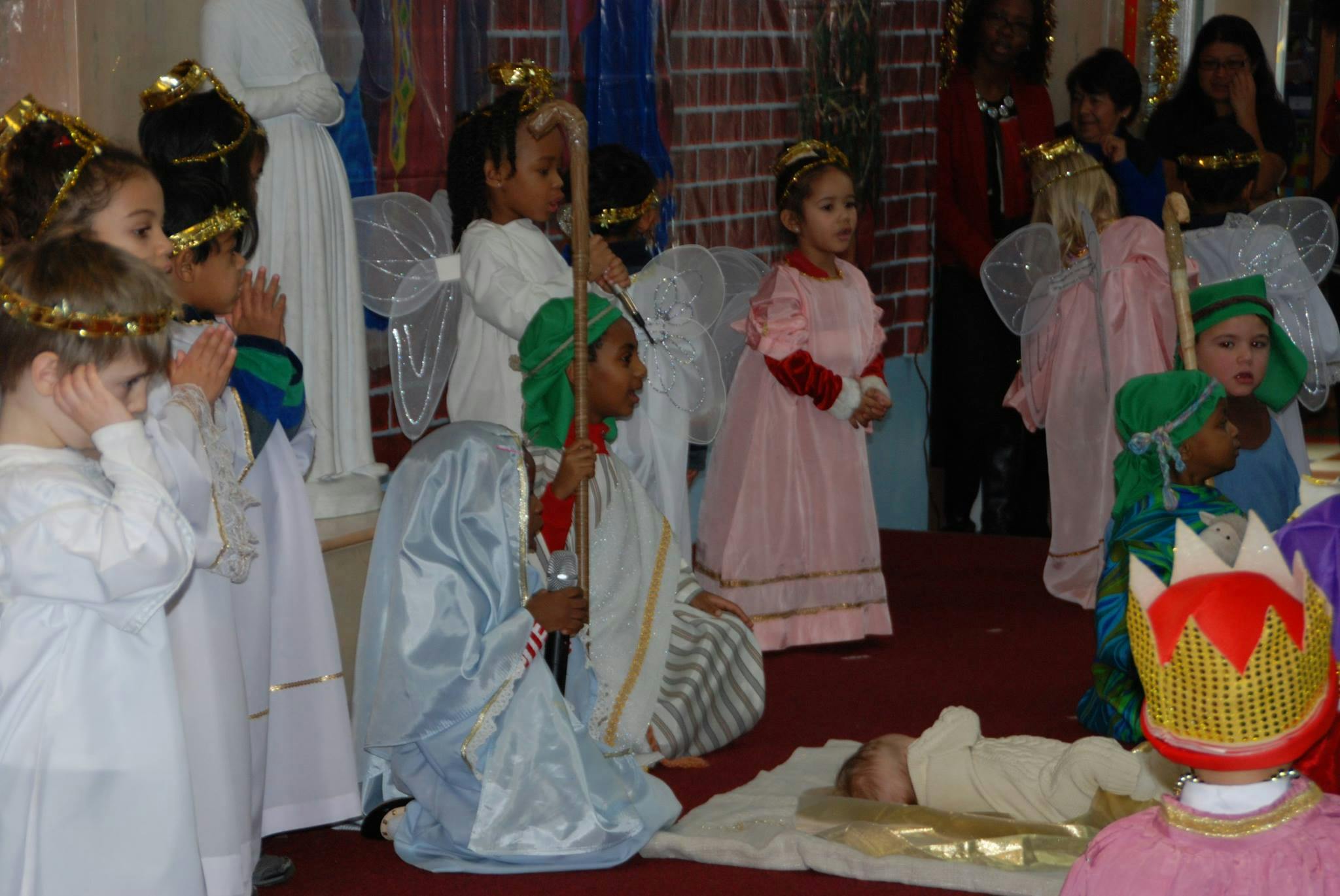 Children in costumes performing a nativity play with a baby doll