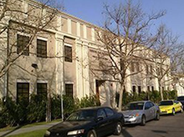 Building with bare trees and cars parked on the street