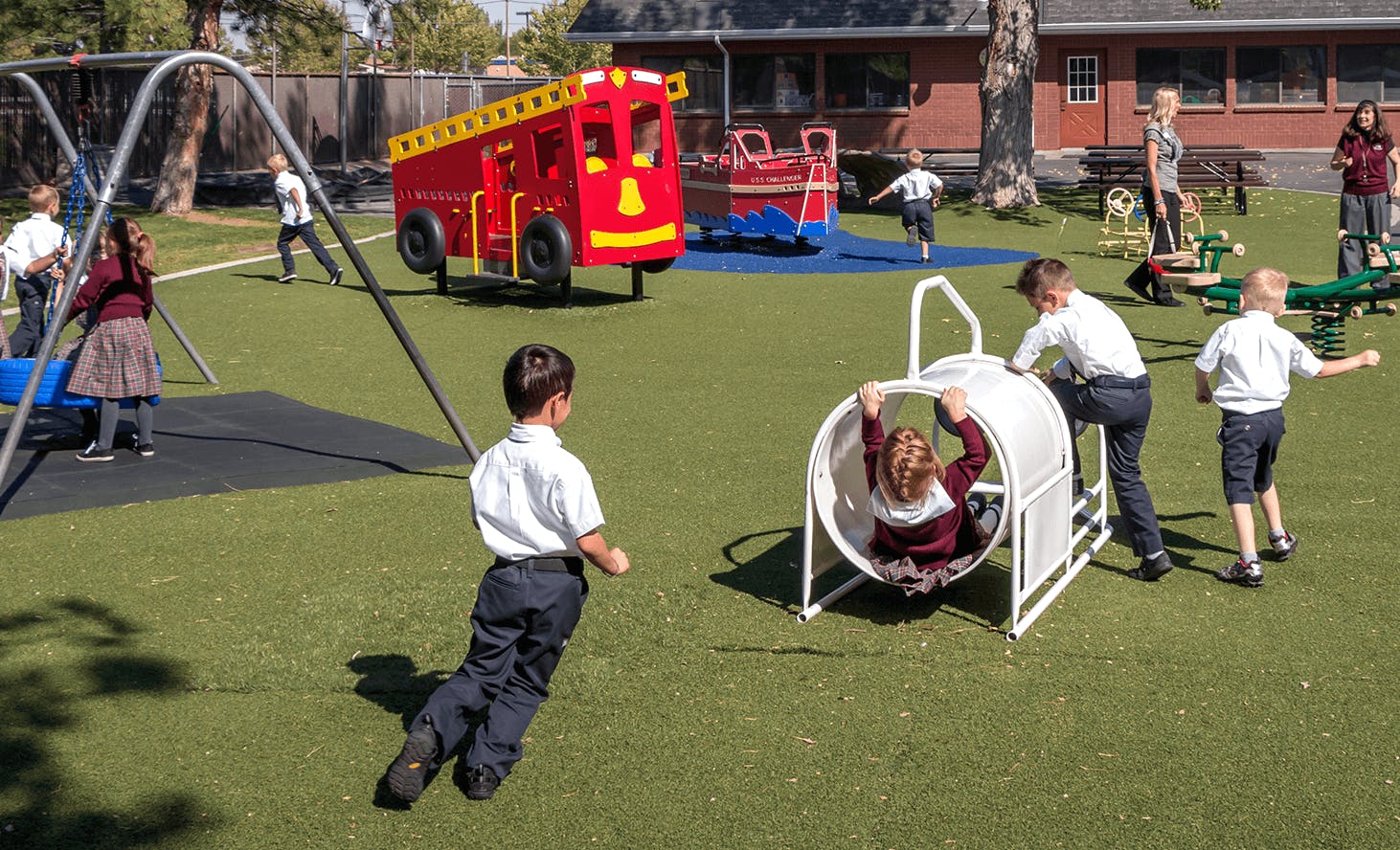 Children playing on a playground with a red fire truck structure