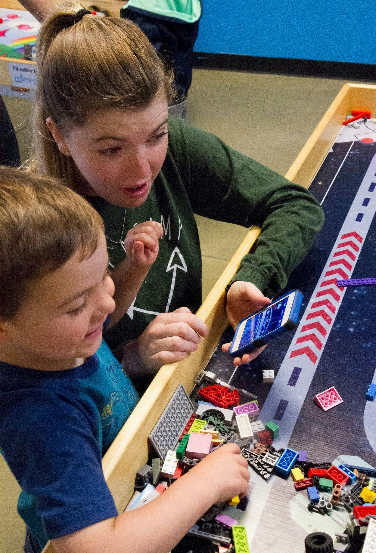 Person and child looking at a phone and building with blocks