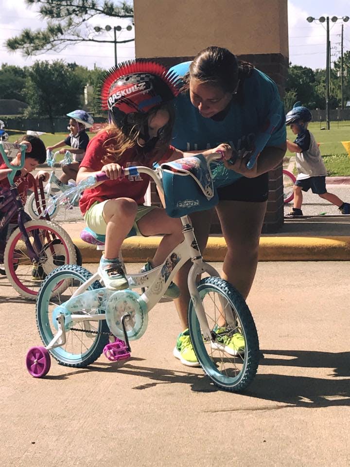 Person helping a child on a bicycle with training wheels