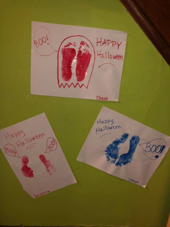 Three Halloween-themed footprint crafts on a green surface