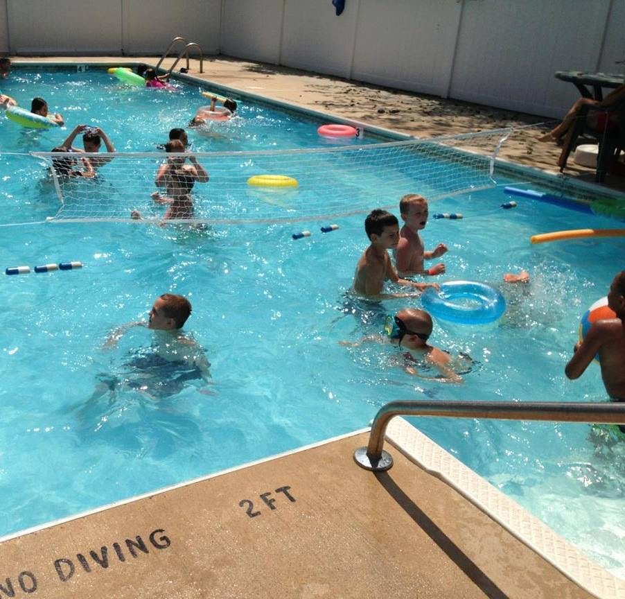 Children swimming in a pool with a net across the middle