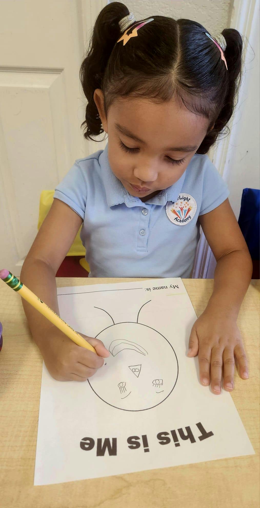 Child drawing on a paper with "This is Me" written on it