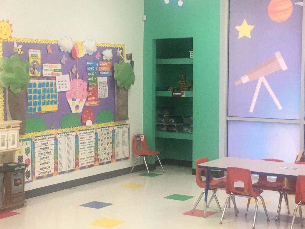 Classroom with bulletin board, shelves, tables, and chairs
