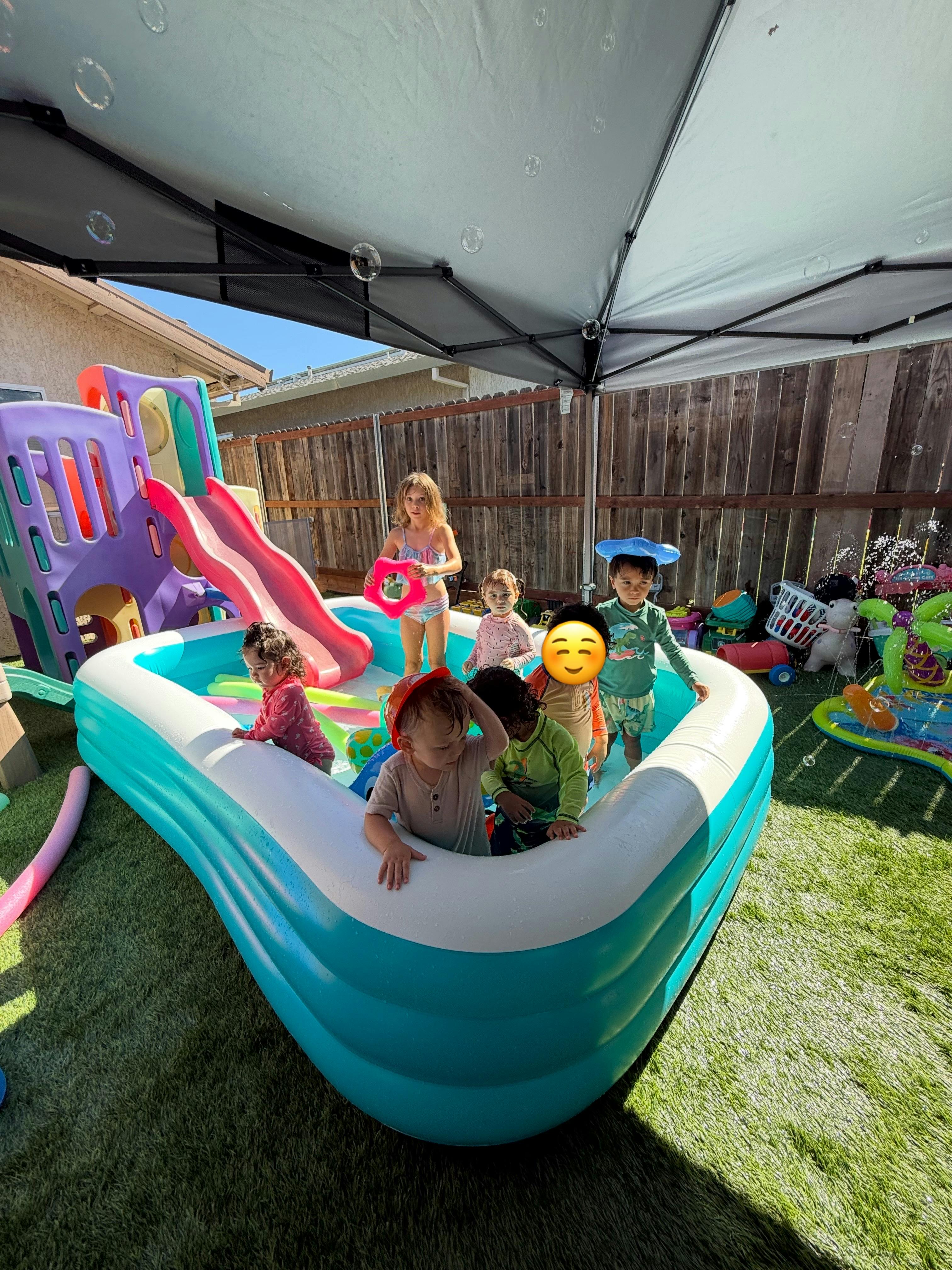 Group of children playing in an inflatable pool in a backyard