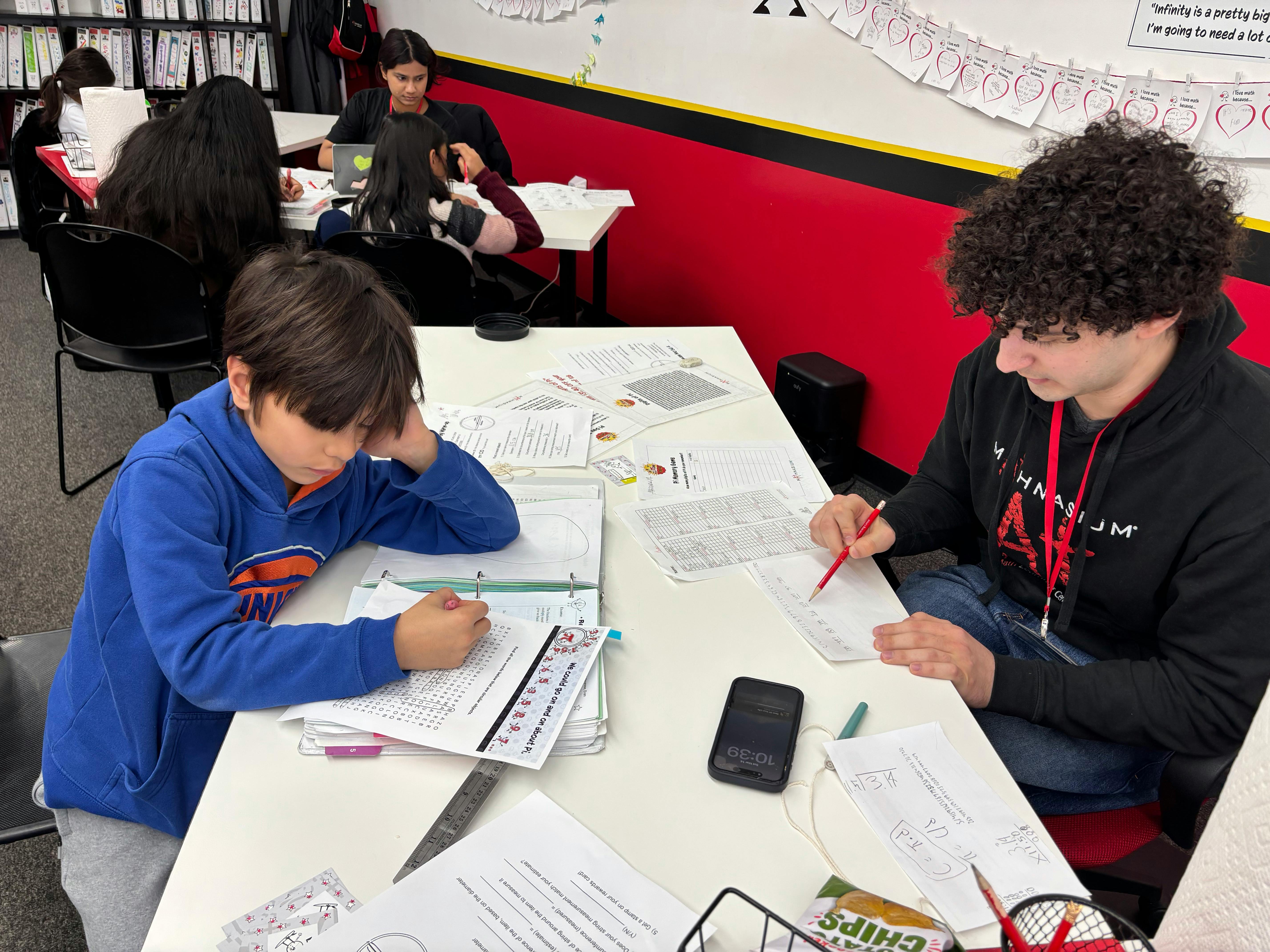 Students working on math assignments at a white table