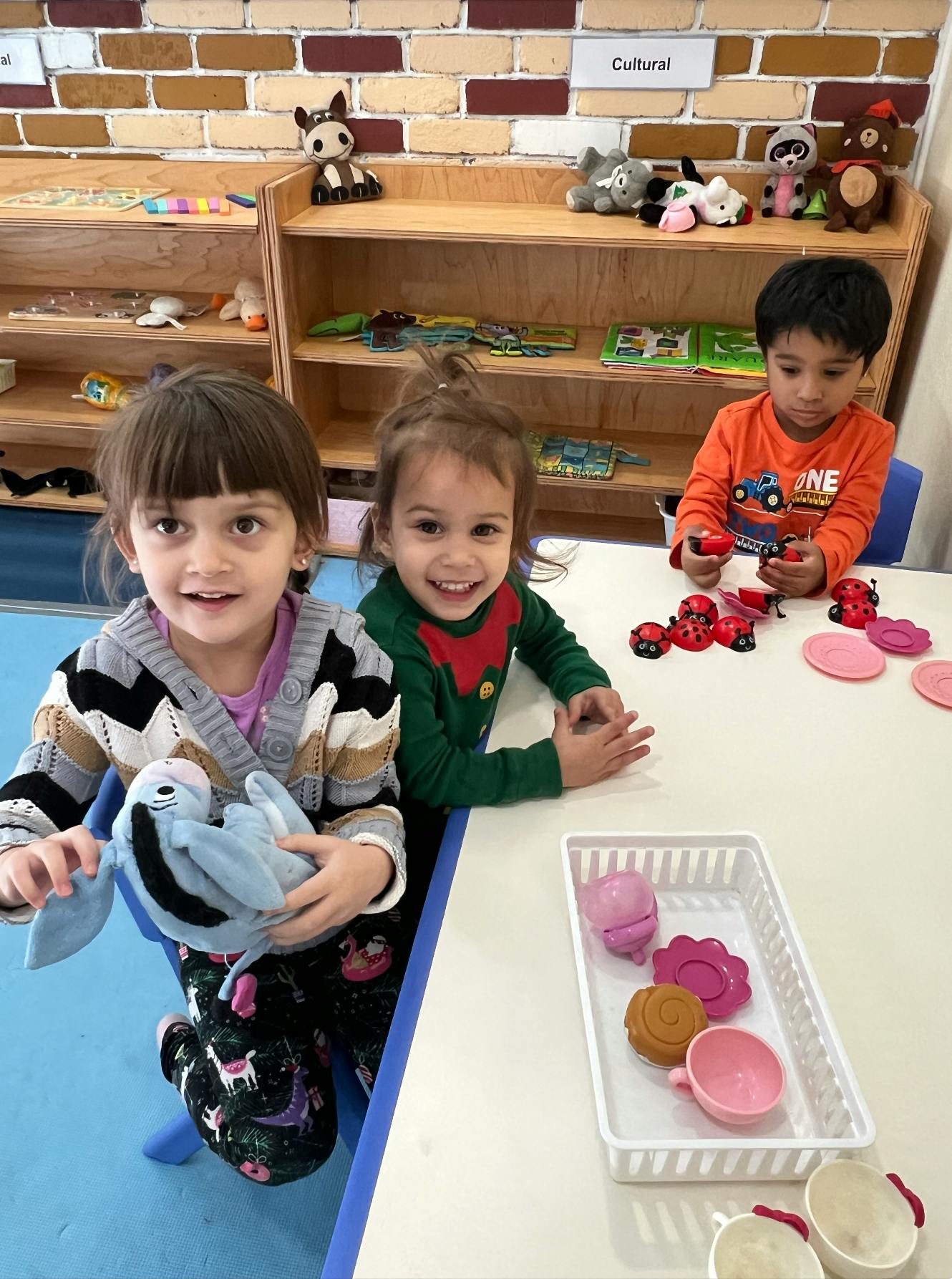 Three children playing with toys at a table in a classroom