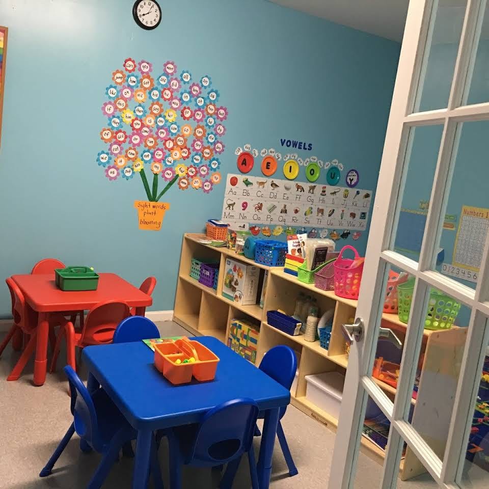 Classroom with small tables and chairs, shelves, and wall decorations