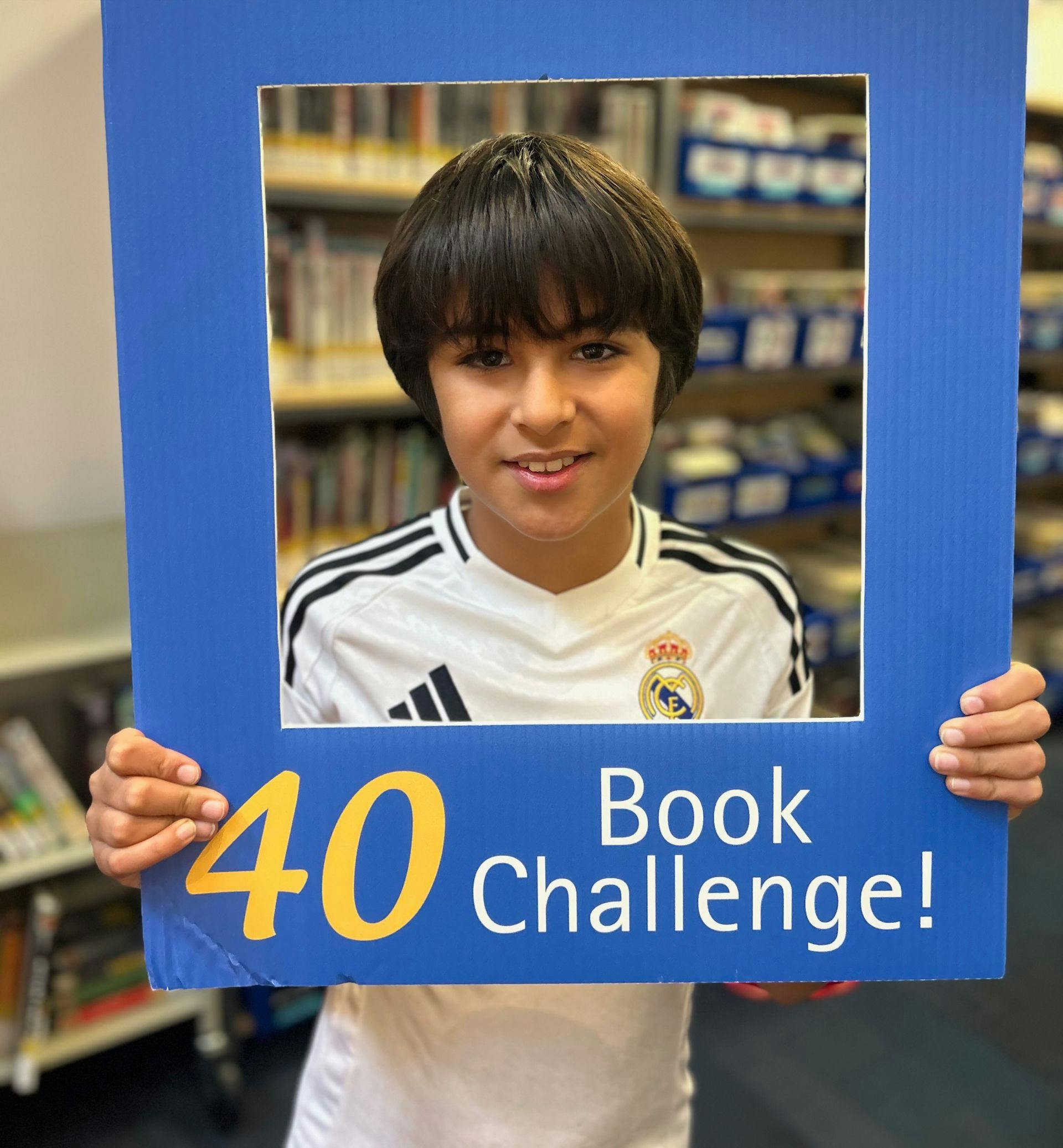 Child holding a blue sign with "40 Book Challenge!" text