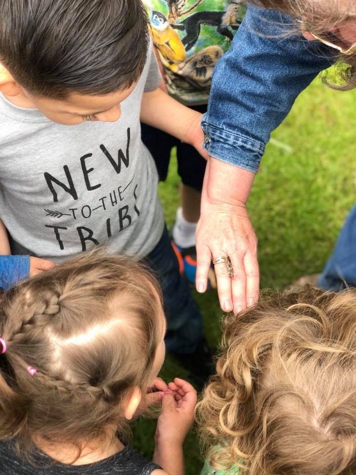 Adult hand touching a child's head, with other children nearby