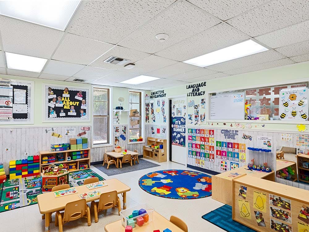 Colorful preschool classroom with tables, chairs, and learning materials
