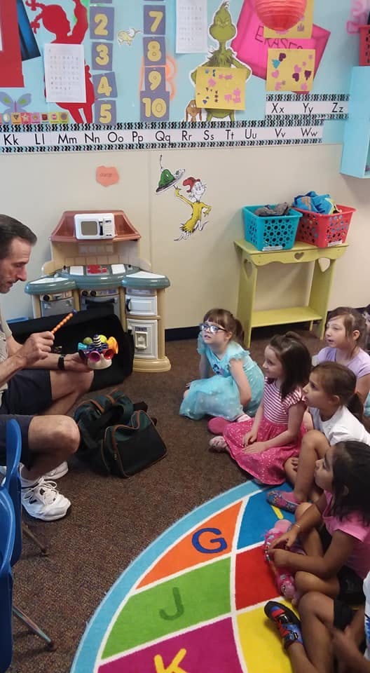 Adult showing children a toy in a classroom